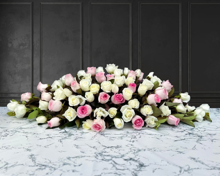 funeral spray of pink and white roses, funeral flowers and casket flowers in white